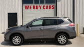 Silver SUV parked in front of a white corrugated metal building with a garage door that reads 'WE BUY CARS' in red letters.
