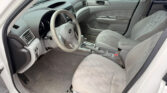 Front interior of a light-gray sedan showing steering wheel, center console, and front seats.