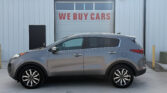 Gray SUV parked in front of a light-gray industrial building with a large garage door that reads 'WE BUY CARS'